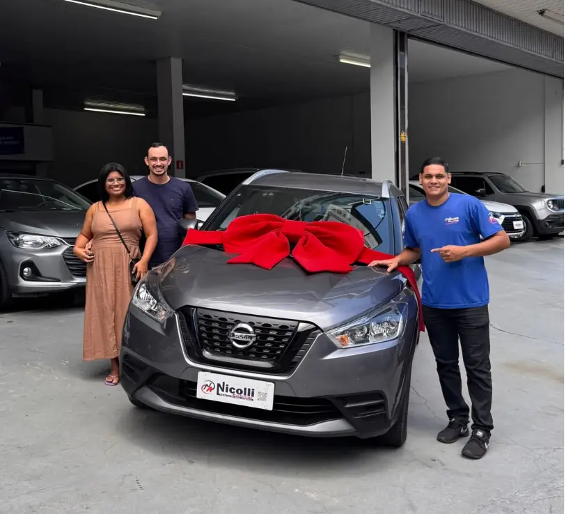 Lucas entregando um Nissan Kicks com laço vermelho a um casal